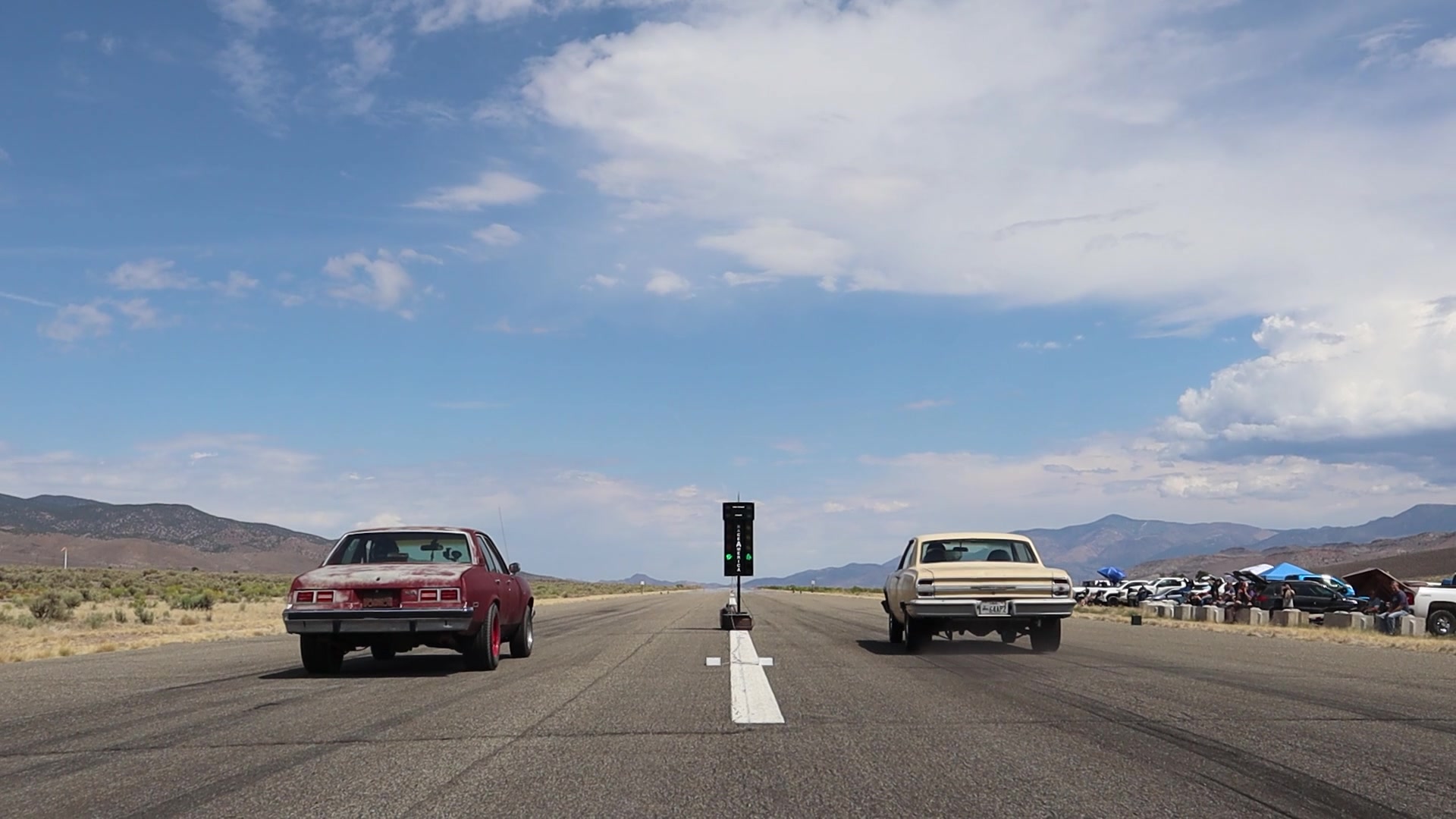 Two classic American cars staged at a desert drag strip